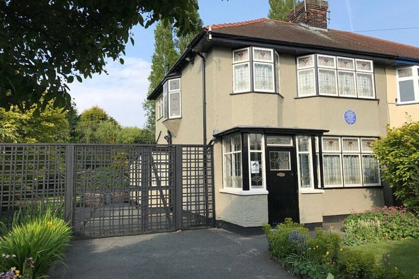 A two-story house with a gated driveway, surrounded by greenery and a clear sky. 5