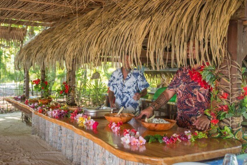 A thatched-roof structure with a wooden counter adorned with flowers and bowls. 2