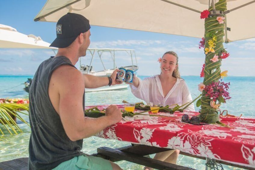 Two people at a table with a red tablecloth, a drink, and a decorative plant. 2