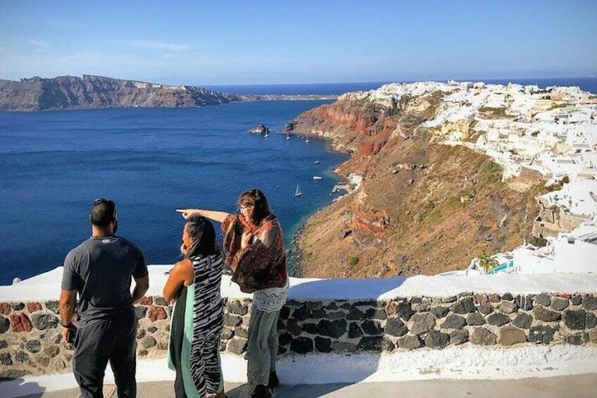 Vista costera con un muro de piedra, un grupo de personas y un pueblo lejano. 4