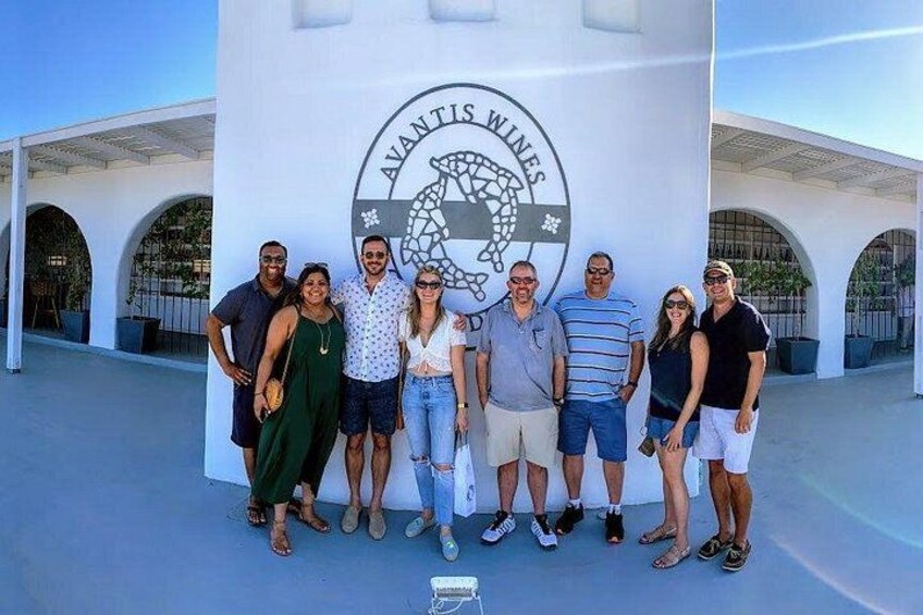 Un grupo de personas frente a un edificio con un logotipo que dice 'AVANTI'S WINES'. 1