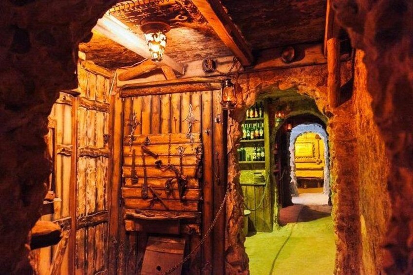 A rustic wooden door with a bell, a green archway, and a lantern above. 4