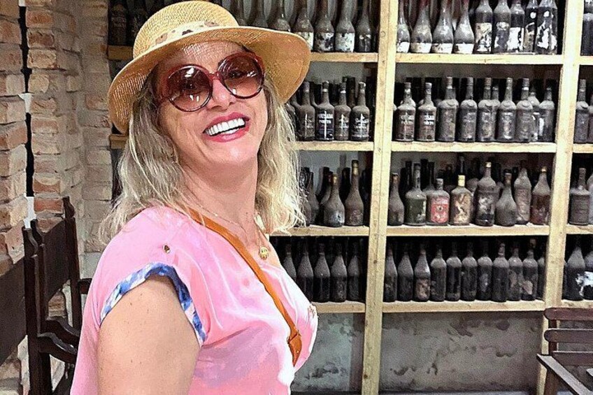 A person standing in front of a wall of old bottles. 2