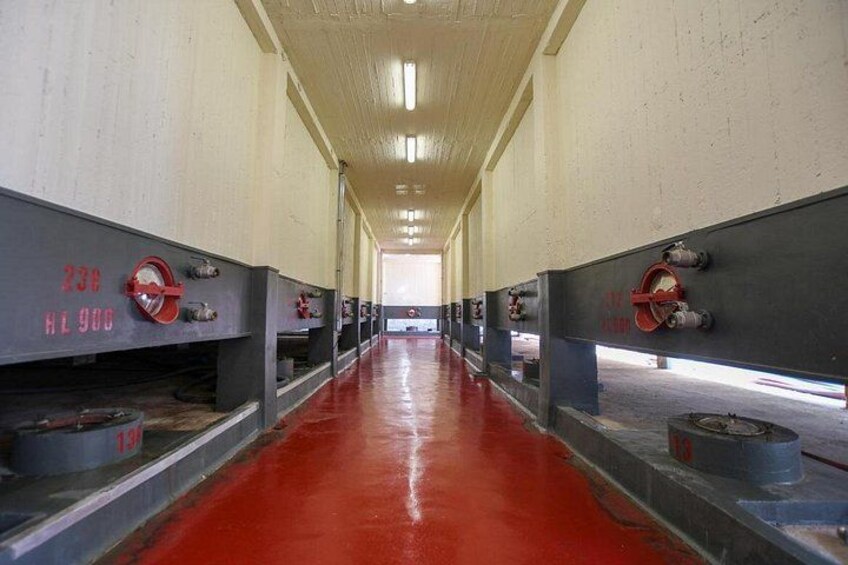 Un lungo corridoio con pavimento rosso e attrezzature industriali su entrambi i lati. 3