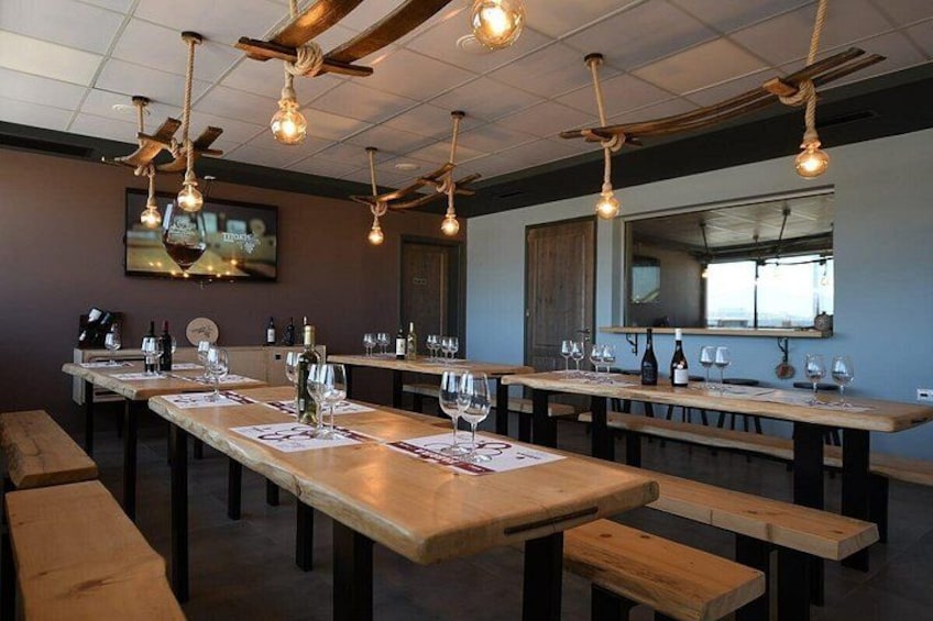 Una sala de degustación con mesas de madera, copas de vino y botellas. 2