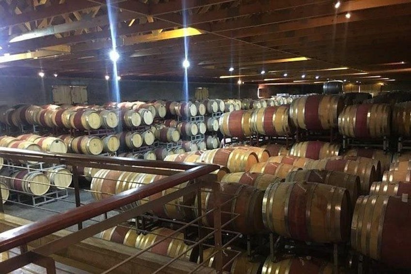 A large number of wooden barrels arranged in rows inside a warehouse. 2