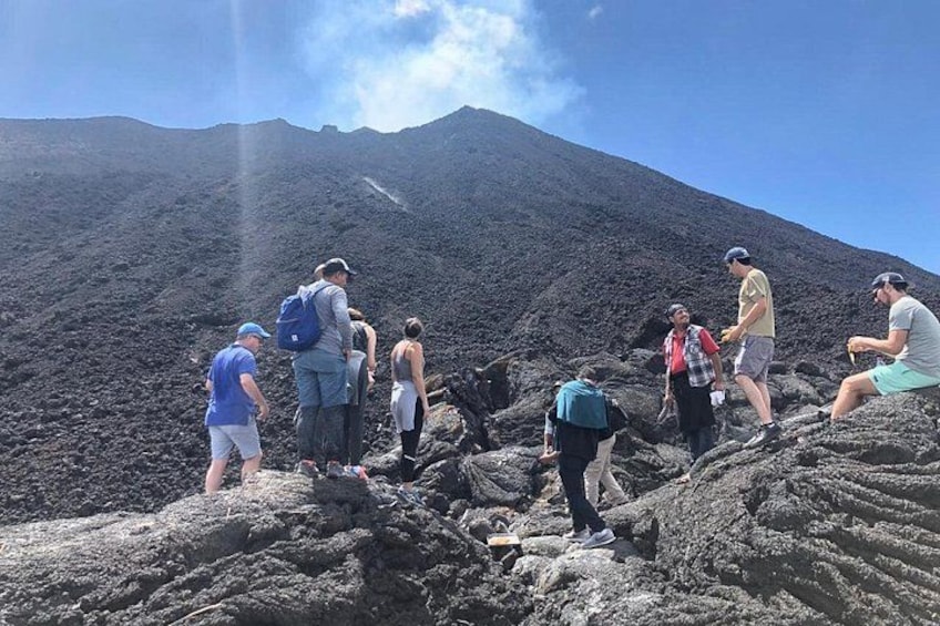 Un grupo de personas caminando por terreno volcánico con una montaña al fondo. 2