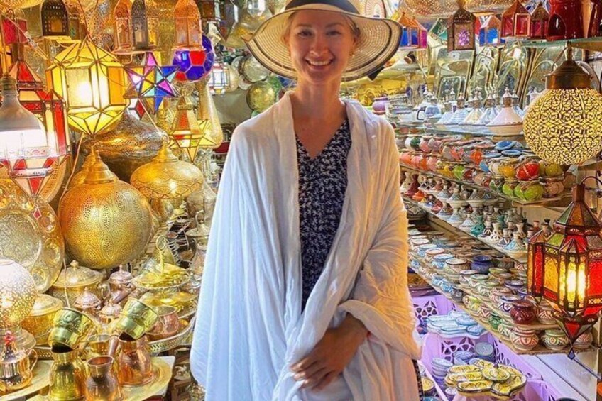 A person standing in a market with various colorful glassware and lanterns. 3
