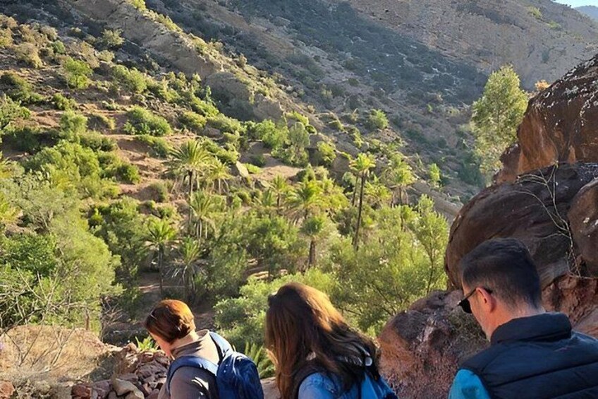 Eine Gruppe Wanderer auf einem steinigen Pfad, mit einer gebirgigen Landschaft im Hintergrund. 2
