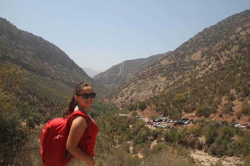 A person in a red shirt standing on a hill overlooking a valley with a group of vehicles parked below. 4