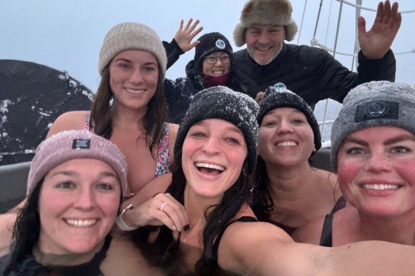 Un gruppo di persone su una barca, con la neve sui loro vestiti e sul ponte. 5
