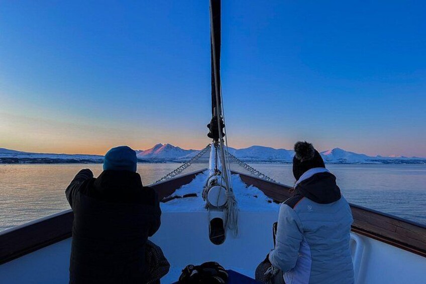 Due persone su una barca, con un paesaggio innevato e montagne sullo sfondo. 1