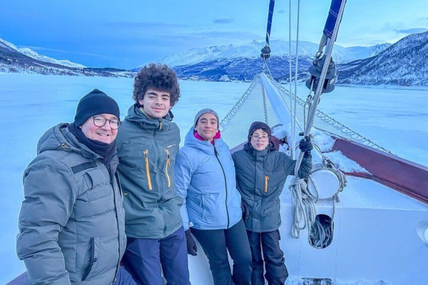 Un gruppo di persone su una barca in un paesaggio innevato, con montagne sullo sfondo. 2