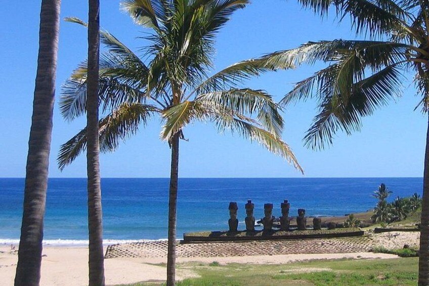 Ein Strand mit Palmen und einer Reihe aus Steinstatuen. 1