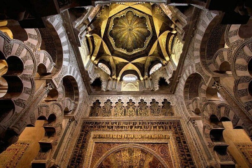Un interior ornamentado con arcos intrincados y un techo ricamente decorado. 4