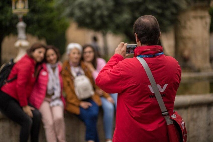 Una persona con una chaqueta roja fotografiando a un grupo de personas sentadas en un muro. 1
