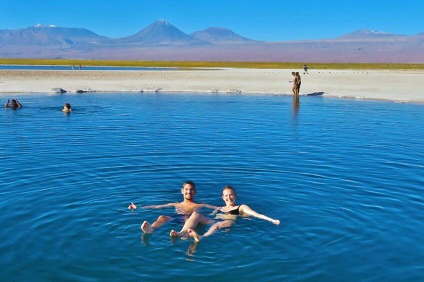 Una piscina geotermica con persone che nuotano, un paesaggio desertico e montagne sullo sfondo. 2