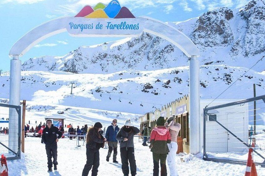 A snowy mountain entrance with a sign reading 'Parques de Farellones' and a ski lift in the background. 2