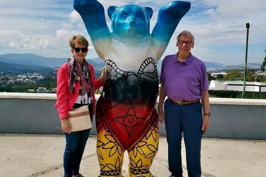 Zwei Personen stehen neben einer farbenfrohen Skulptur mit blauem, rotem und gelbem Dekor. 2