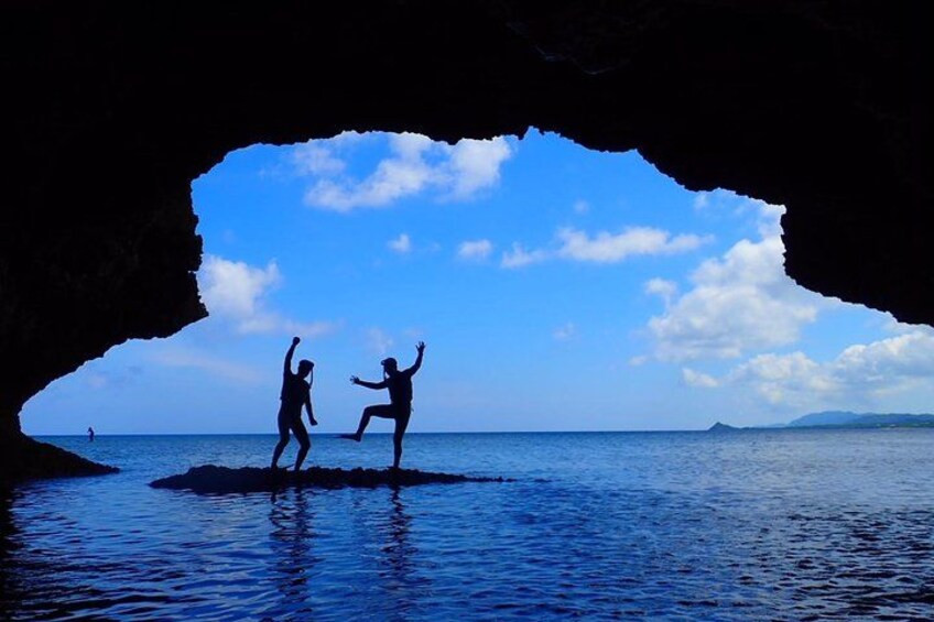 Two people jumping out of a cave into the water. 4