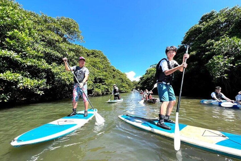 People paddleboarding on a river surrounded by dense greenery. 3