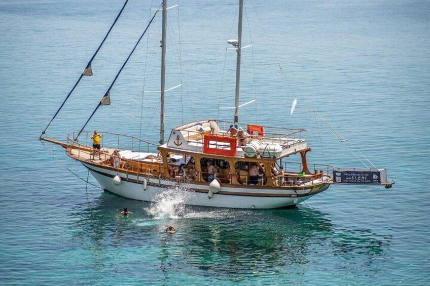 A sailboat with multiple masts and a cabin, sailing on a calm body of water. 2