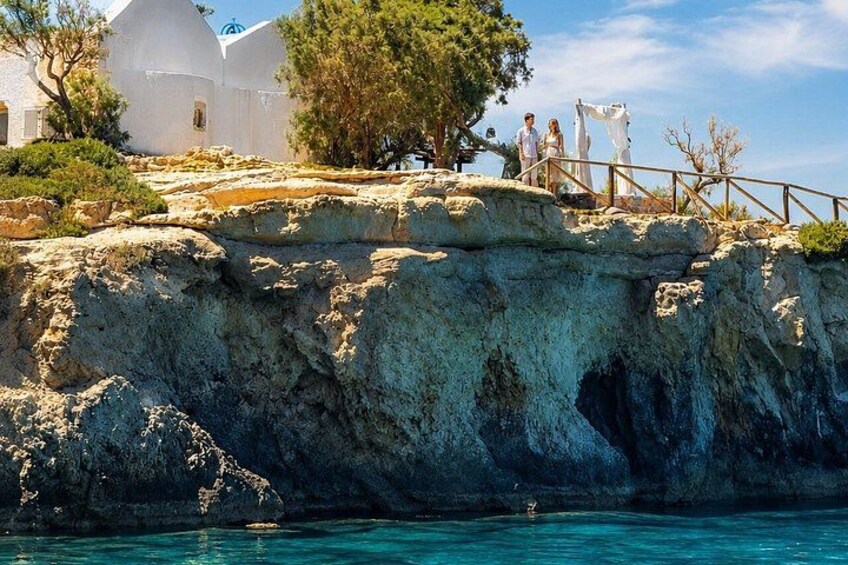 Une côte rocheuse avec un bâtiment blanc, un pont en bois et une mer d’un bleu limpide. 3
