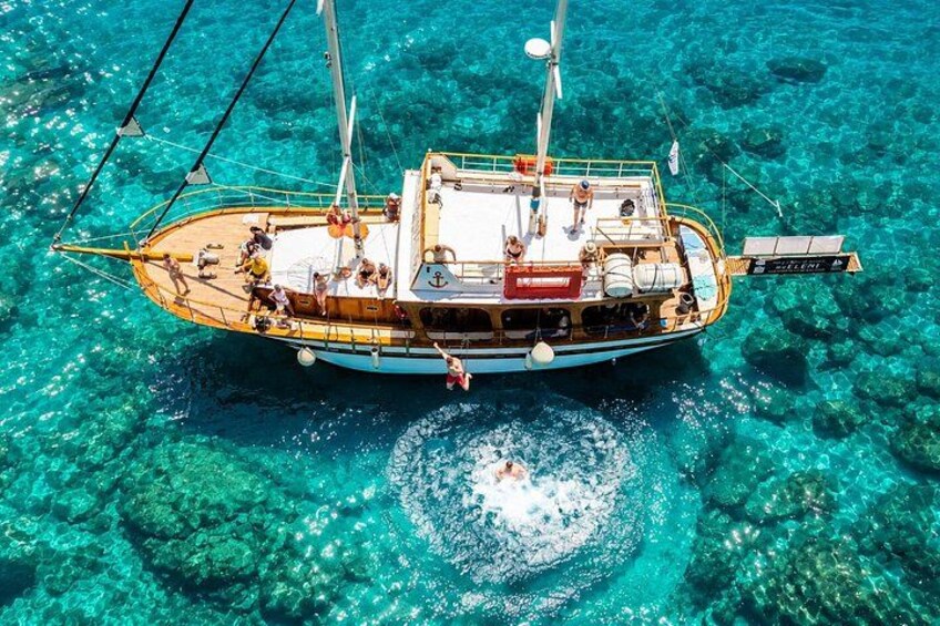 Un bateau en bois, avec des personnes à bord, flottant sur une eau turquoise et cristalline. 4