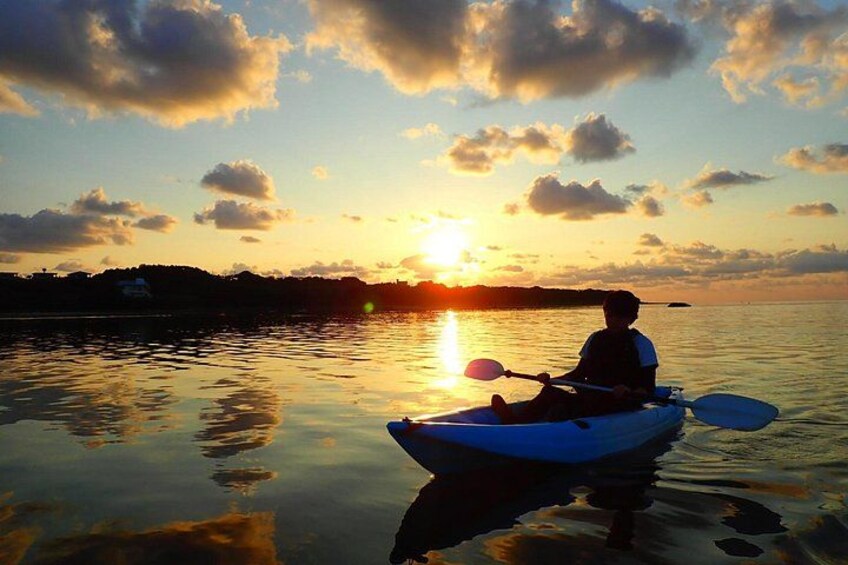 A person kayaking on calm water during sunset. 2