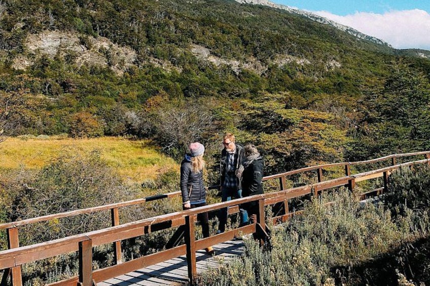 Two people on a wooden bridge with a mountainous landscape in the background. 3