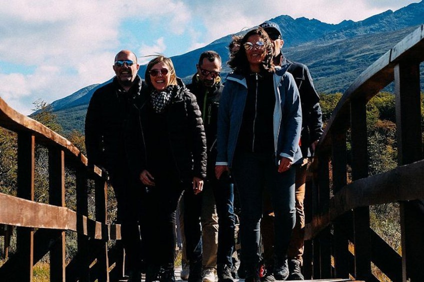 A group of people on a wooden bridge with a mountainous landscape in the background. 5