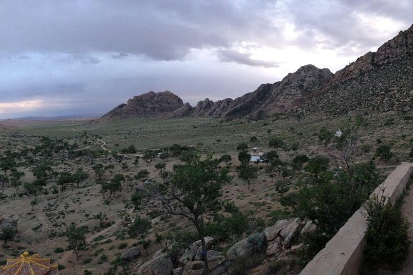 A desert landscape with sparse vegetation, rocky mountains, and a clear sky. 5