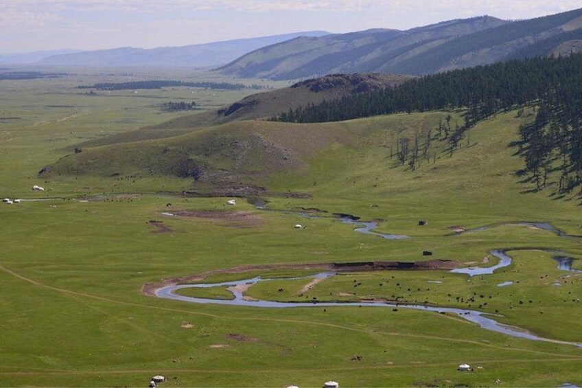 A vast green valley with winding streams, rolling hills, and scattered trees. 2