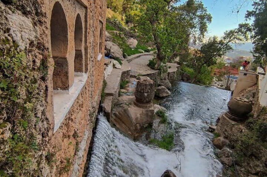 Un puente de piedra con arcos, un arroyo serpenteante y un paisaje rocoso. 5