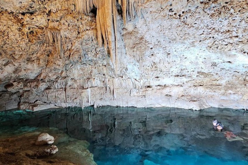 A cave with stalactites and a diver swimming in a pool. 4