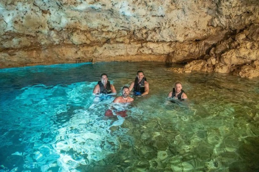 A group of people in a natural pool with clear water and rocky walls. 2