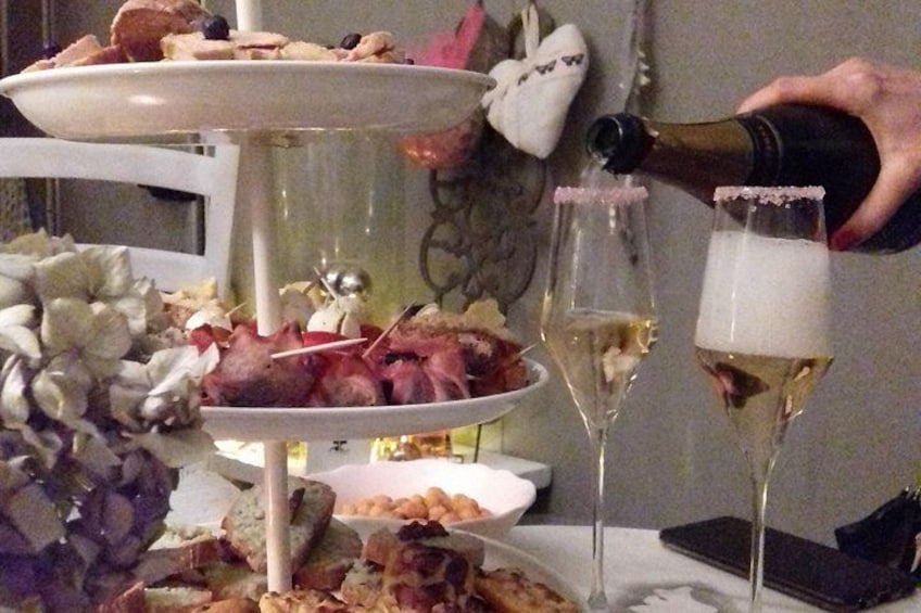 A three-tiered dessert stand with various pastries and a bottle of champagne being poured into a glass. 1