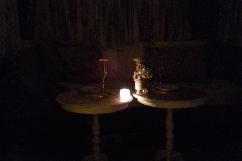 Two round tables with a glass and a small plant on each. 4