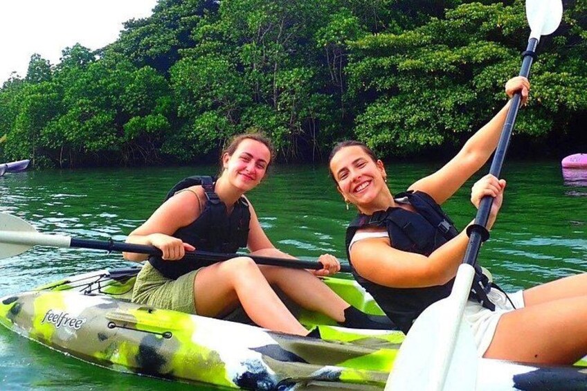 Two people kayaking on a green and white kayak with a forested background. 4