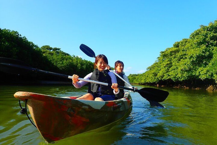 Two people kayaking on a river surrounded by lush greenery. 2