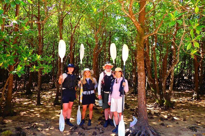 Four people standing in a forest with paddles. 5