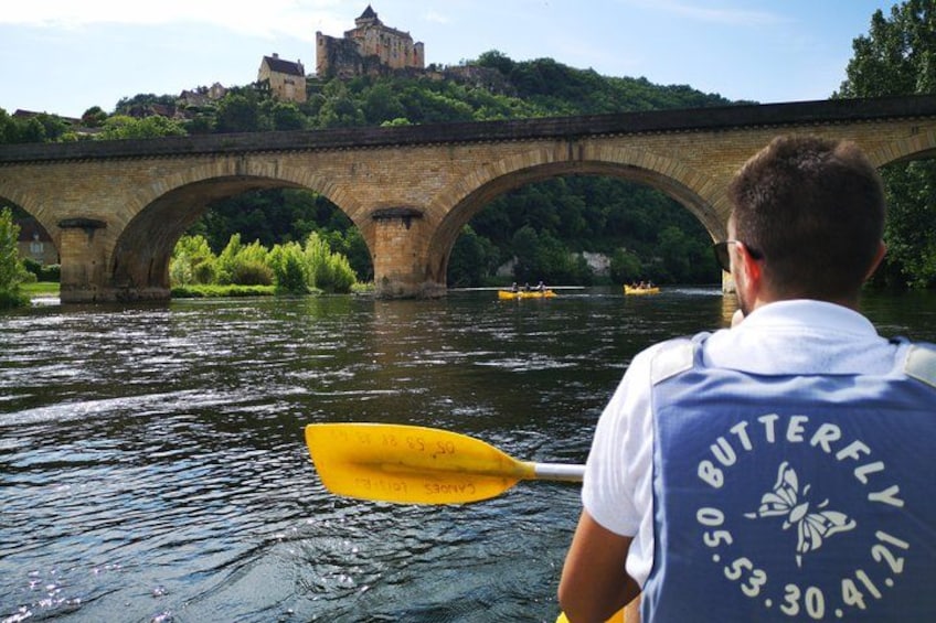 A man paddling a yellow canoe on a river, a stone bridge, and a castle in the background. 3