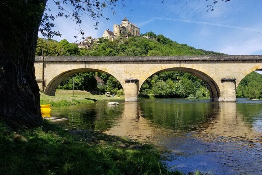 A stone bridge over a river with a castle in the background. 2