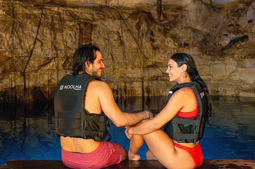 Two people sitting by a pool with cave-like rock formations in the background. 4