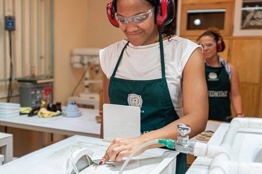 A person wearing an apron and safety goggles, working with a machine. 4