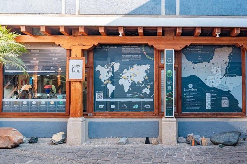 A building with wooden beams, a sign reading 'Jade,' and two large informational maps. 2