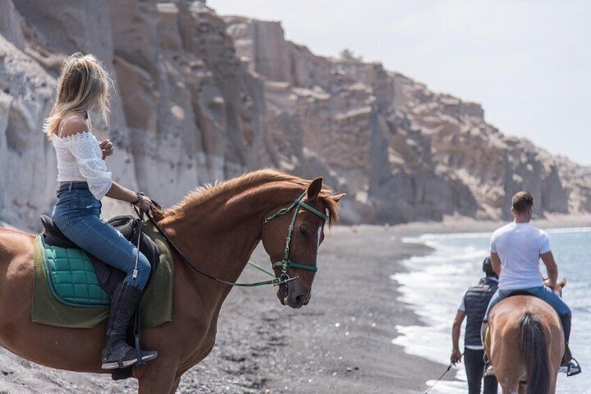 Een persoon die op een paard rijdt op een strand met rotsachtige kliffen op de achtergrond. 3