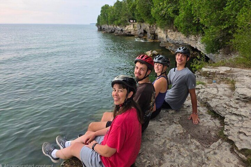 Quatre personnes sont assises sur un rebord rocheux, au bord d’une étendue d’eau. 2