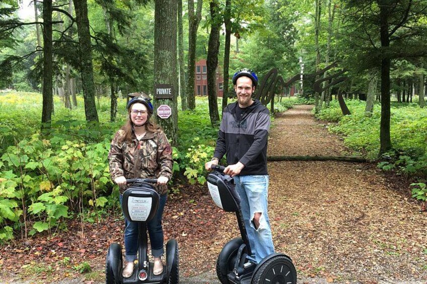 Two people on Segway devices in a forested area with a sign that reads 'PRIVATE'. 2