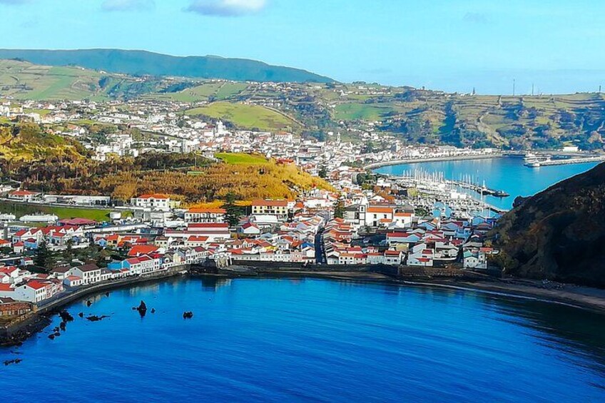 Un pueblo costero con un puerto, edificios y colinas al fondo. 2
